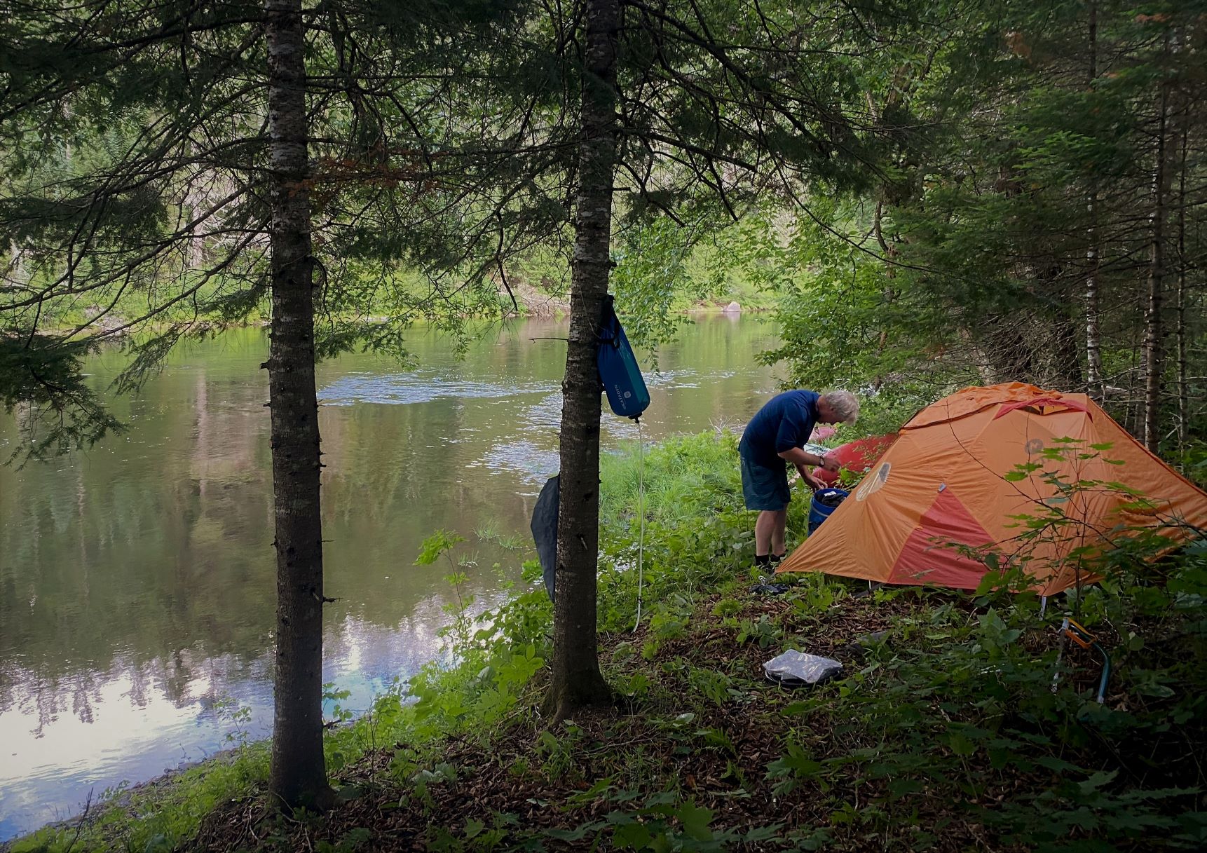 A man setting up a tent beside the Dumoine River