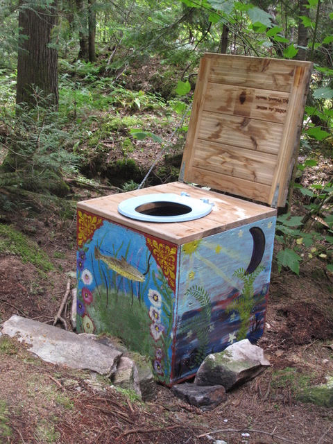 Une boîte de toilette peinte située le long du sentier